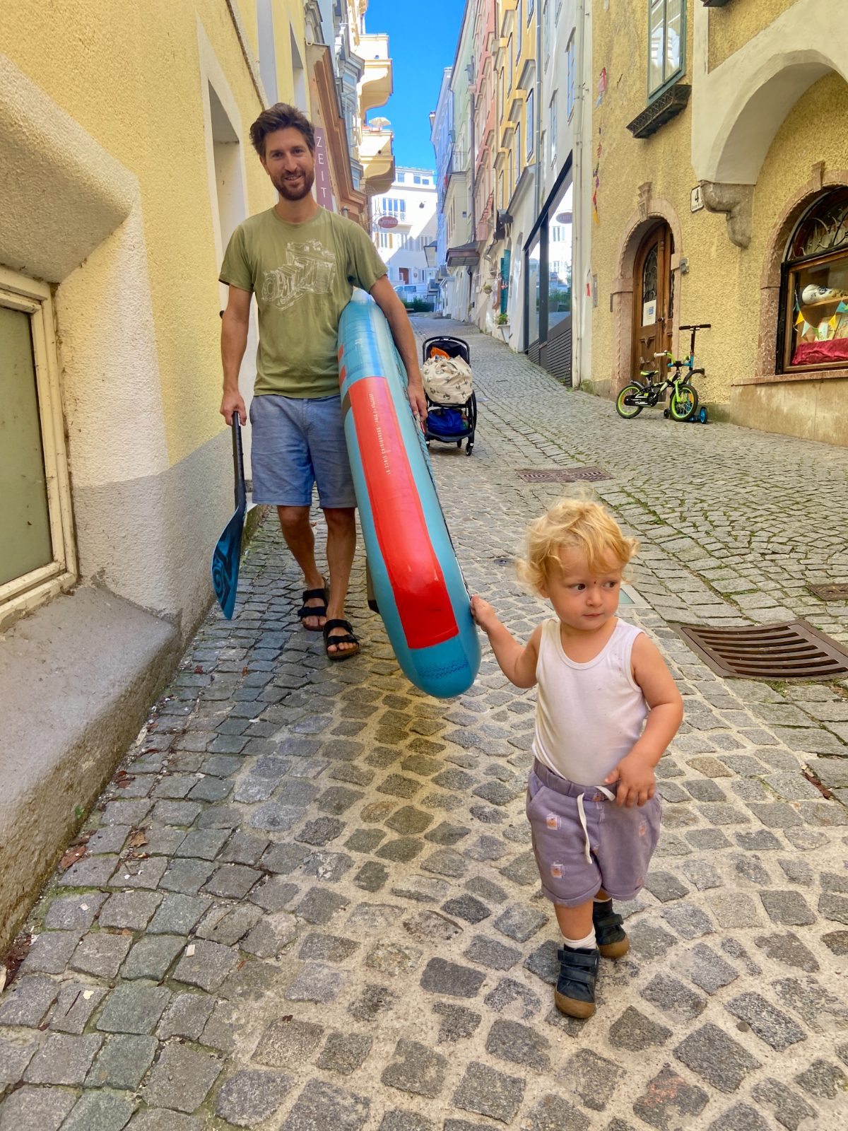 Vater mit Stand-up-Board und Kind in einer Altstadtgasse in Gmunden